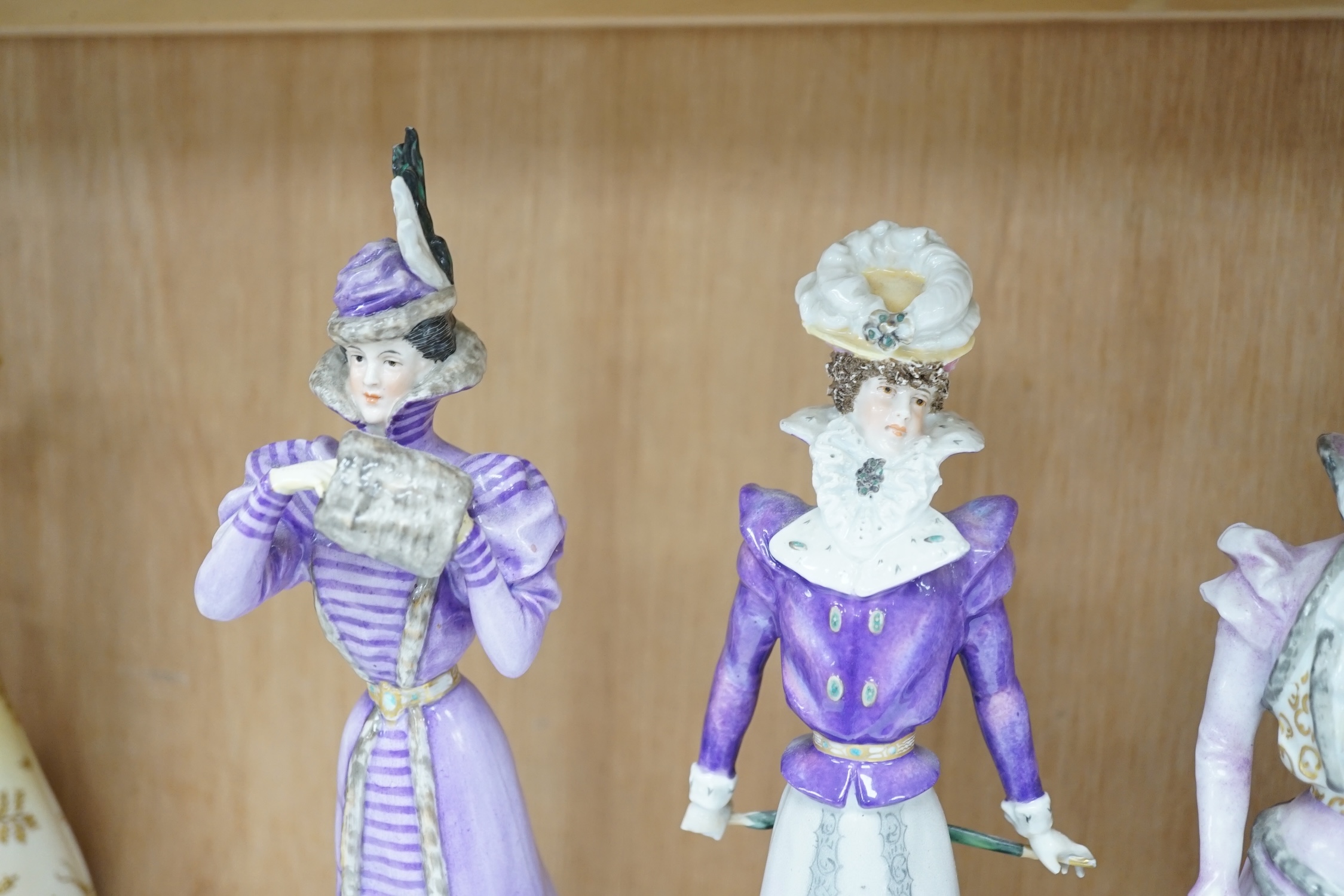 Four German Plaue porcelain figures of Edwardian fashionable ladies, tallest 27.5cm high. Condition - poor some chips